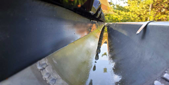 Gespülte Dachrinne nach einer gründlichen Regenrinnenreinigung befreit Laub, Moos und Schmutz