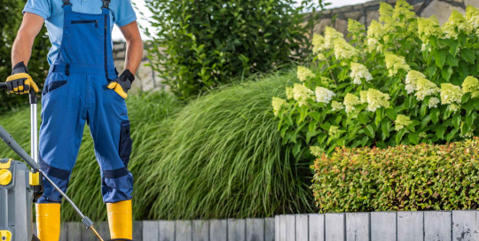 Der Gärtner setzt den Hochdruckreiniger ein, um hartnäckigen Schmutz von Terrassenfliesen zu entfernen